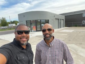 Two men standing in front of retail building